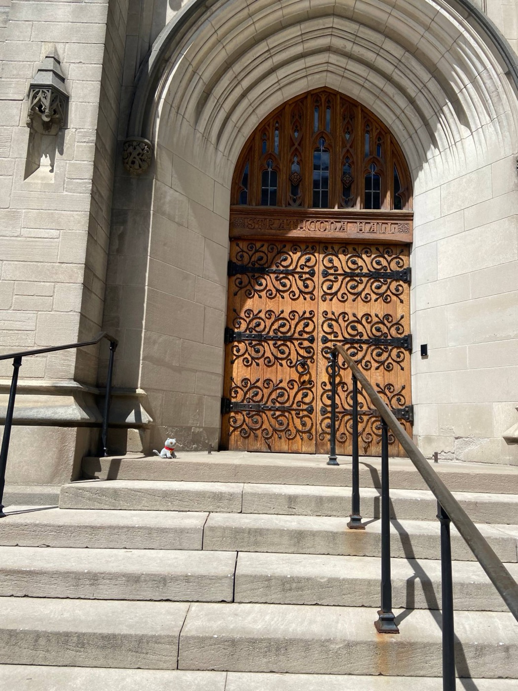 Judy sitting on the stone steps beside the carved wooden doors of Strathcona Hall at Yale